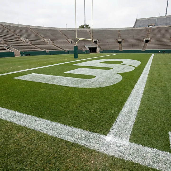 Empty football stadium view from the end zone with a large white Womp Designs logo on the turf.