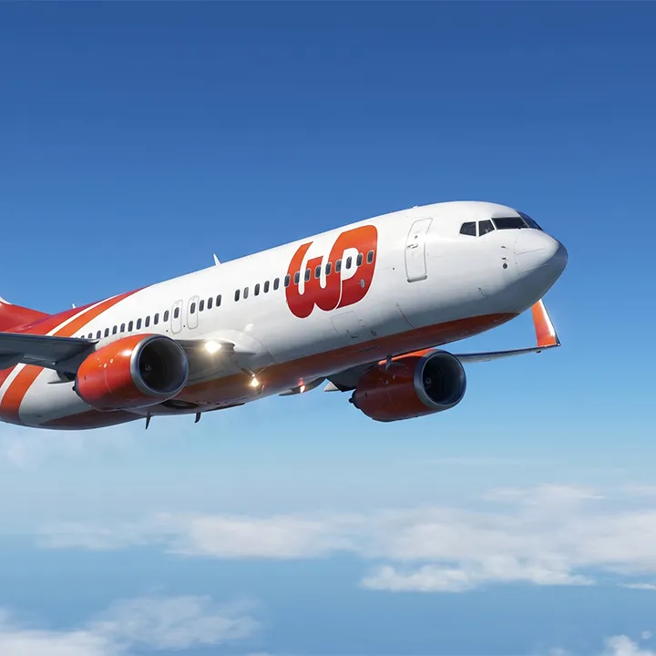 Airplane flying in a blue sky with an orange and white livery and a large Womp Designs fuselage logo.