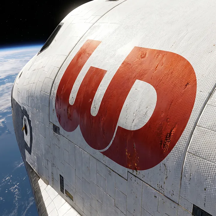 Space shuttle orbiting Earth with a large red and orange Womp Designs logo on its fuselage.