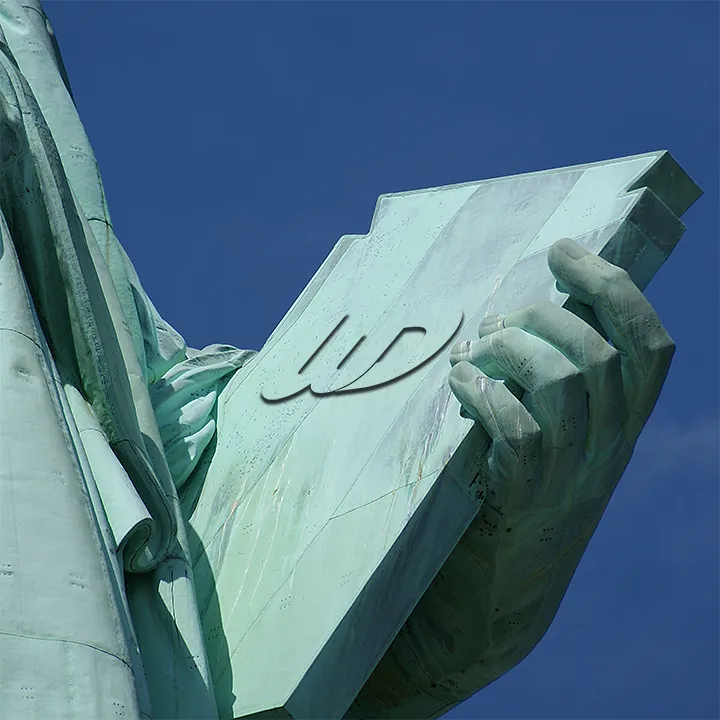 Close-up of the Statue of Liberty's hand holding a tablet with a subtle Womp Designs logo on the copper.